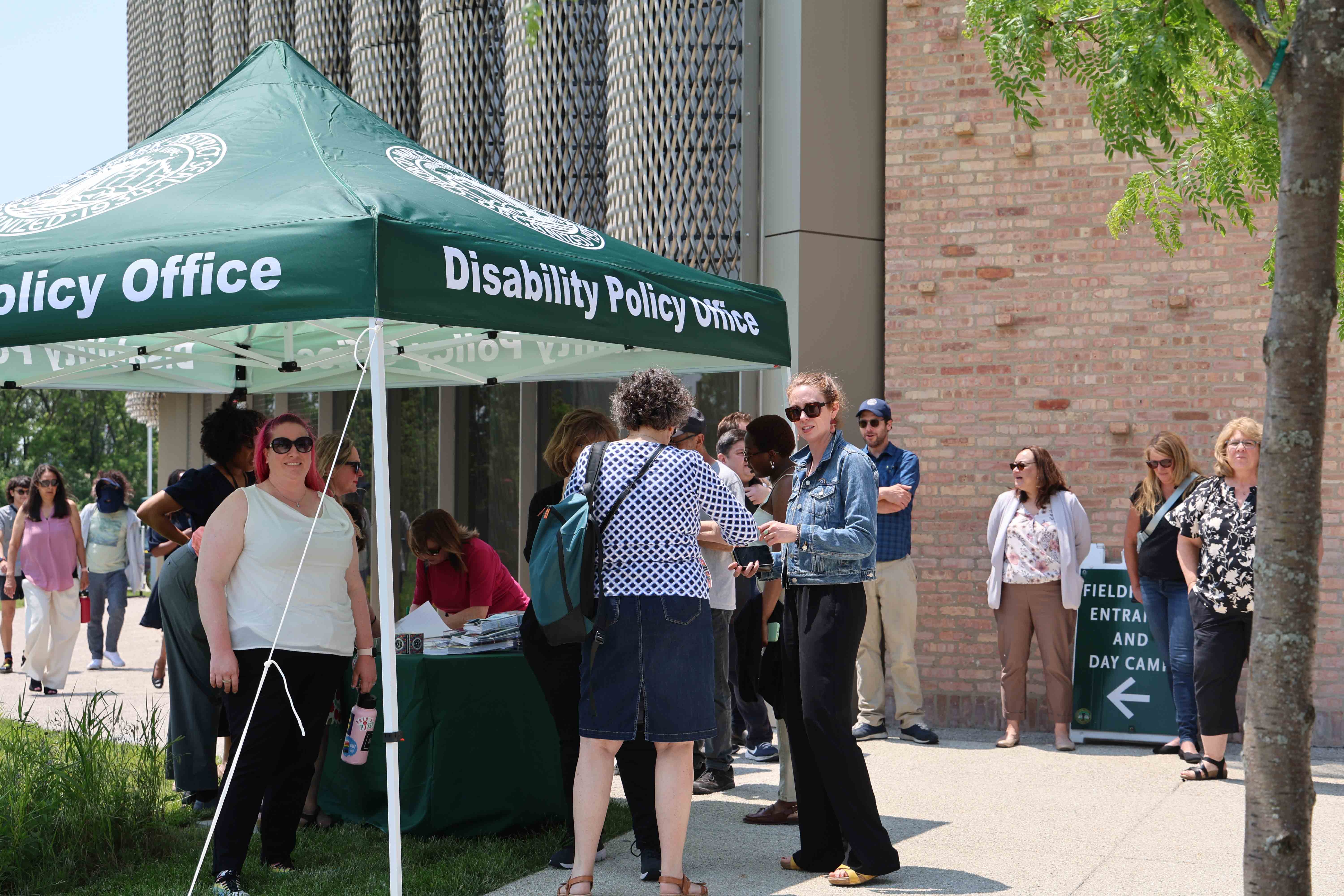 People gather at an outdoor Disability Policy Office booth.